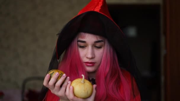 Joven mujer caucásica con disfraz de bruja sosteniendo calabaza de Halloween en casa. - Imágenes, Vídeo