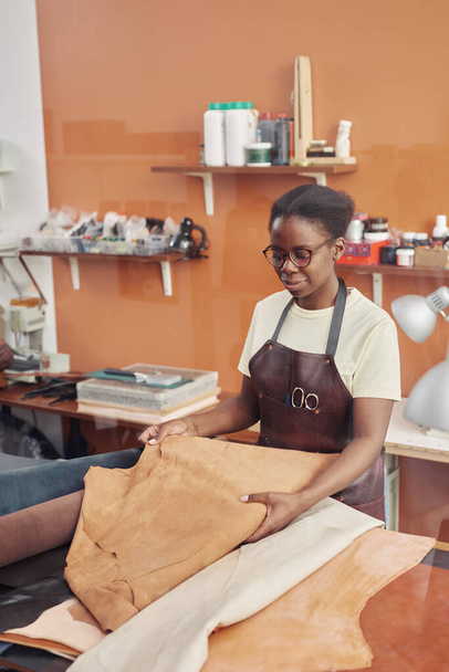 Deriyle çalışan ve atölyede el yapımı parçalar yapan genç siyahi bir kadının dikey portresi. - Fotoğraf, Görsel