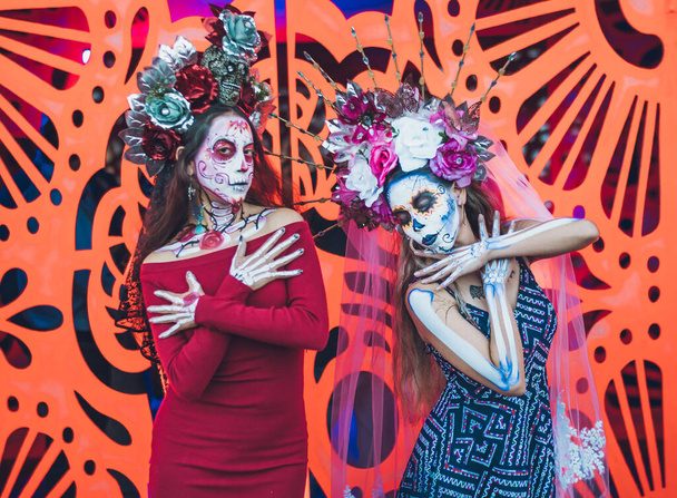 Mexická žena oblečená a charakterizovaná jako katrina pro Den smrti slavnosti, za ní oranžové pozadí jako květ cempasuchil. - Fotografie, Obrázek