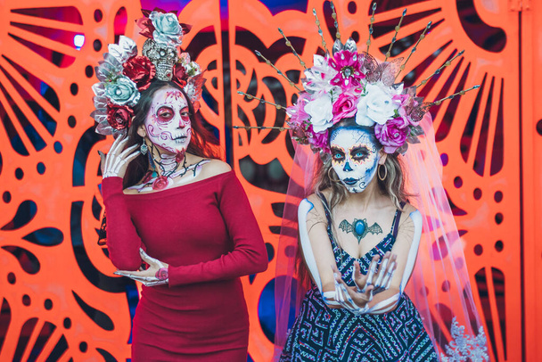 Мексиканка одета и охарактеризована как катрина в День Мертвых, позади нее оранжевый фон, как цветок цемпасучил. - Фото, изображение
