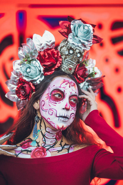 メキシコの女性は,死者の祭りの日にカトリーナを着て特徴づけました, 彼女の背後にあるオレンジ色の背景 ケンパシルフラワーのような. - 写真・画像