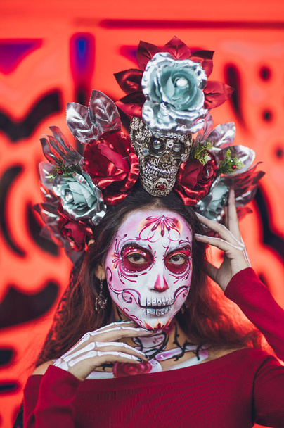 Mexikanische Frau, gekleidet und charakterisiert als Catrina für das Fest der Toten, hinter ihr ein orangefarbener Hintergrund wie die Cempasuchil-Blume. - Foto, Bild