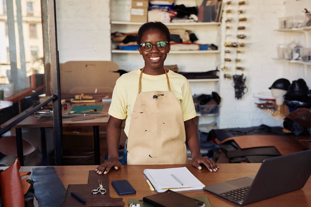 Portrét ženského drobného podnikatele s úsměvem na kameru při pózování v kožené dílně, kopírovací prostor - Fotografie, Obrázek