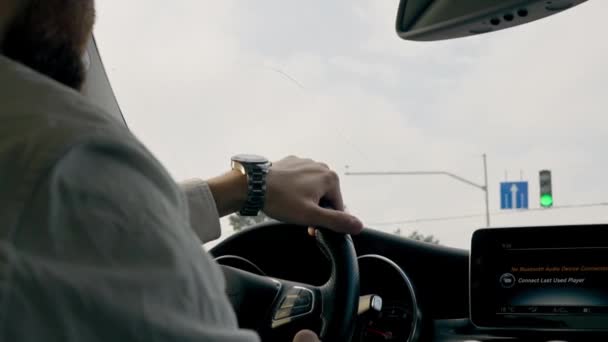 detailní záběr rukou s hodinkami řidiče za volantem v interiéru luxusního auta jedoucího ve městě - Záběry, video