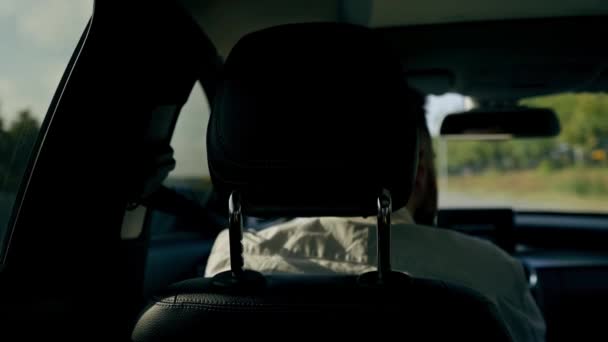 interior de couro preto de um carro de luxo vista do banco traseiro do passageiro no espelho lateral do motorista longa viagem - Filmagem, Vídeo