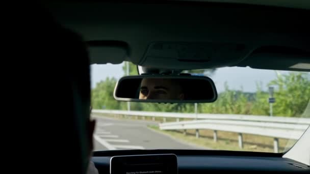 der Fahrer am Steuer eines Luxusautos fährt die Autobahn entlang und blickt in den Rückspiegel - Filmmaterial, Video