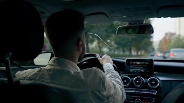 back view mies liikemies ajaa ylellinen auto ympäri kaupunkia musta nahka sisustus näytön liikenneruuhkat - Materiaali, video