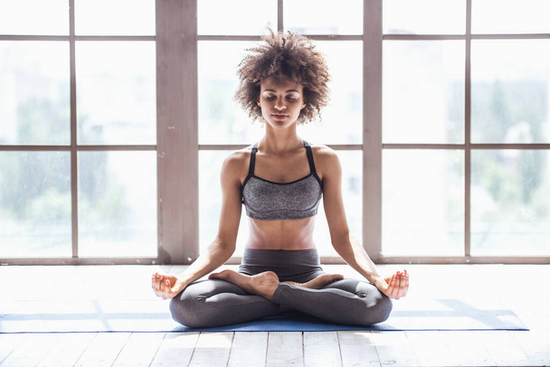 Aantrekkelijk meisje in sportkleding is mediteren tijdens het doen van yoga - Foto, afbeelding