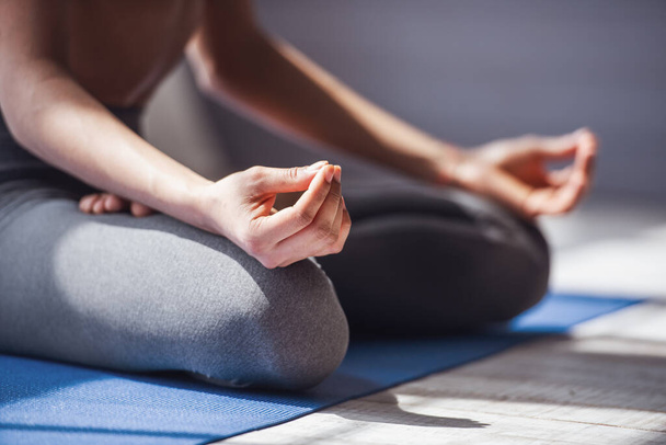 Image recadrée de fille roulant tapis de yoga en vêtements de sport méditant sur tapis de yoga - Photo, image