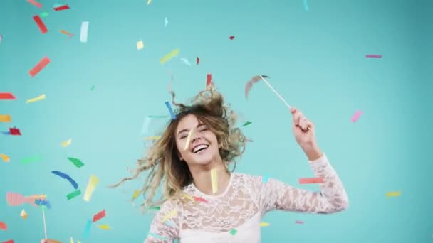 Celebrate, party and face of a woman with confetti isolated on a blue background in a studio. Happy, dance and portrait of a young girl at an event with dancing energy in a photobooth for celebration. - Footage, Video