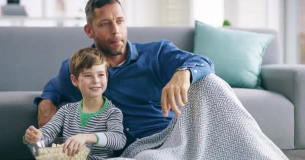 Rodina, popcorn a otec sledující televizi se svým synem na pohovce v obýváku. Láska, úsměv nebo šťastný s mužem a chlapcem streaming film, film nebo video v bytě. - Záběry, video