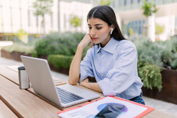 Jeune femme d'affaires travaillant sur un ordinateur portable assis à l'extérieur. Technologie, éducation et style de vie des entreprises. - Photo, image