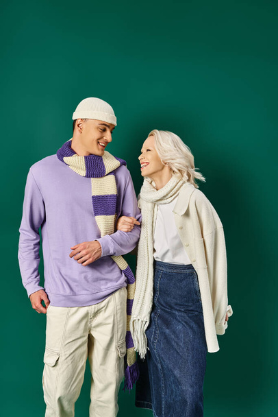 elegante pareja en traje de invierno, mujer feliz posando con el hombre en ropa de abrigo sobre fondo turquesa - Foto, Imagen
