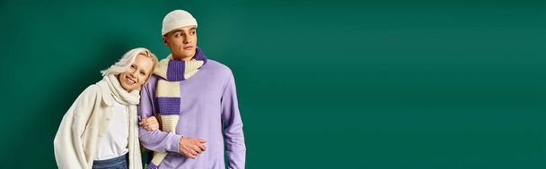 estandarte atuendo de invierno, mujer feliz apoyándose en el hombre con ropa elegante sobre fondo turquesa - Foto, Imagen