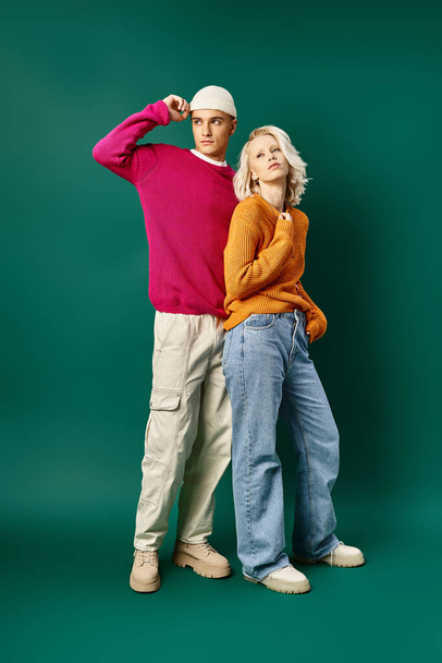 fashionable models in winter outfits posing together on turquoise background, young stylish couple - Photo, Image