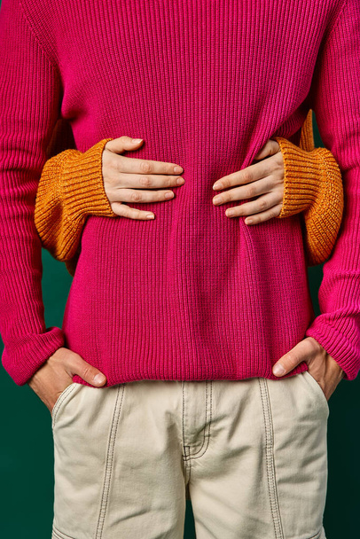 partial view of woman hugging boyfriend in pink knitted sweater, hands of loving couple - Fotoğraf, Görsel