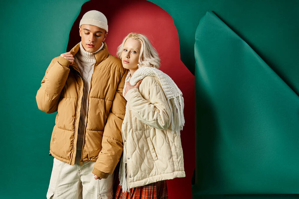 élégant jeune couple en blanc vestes d'hiver posant ensemble sur le rouge avec toile de fond turquoise - Photo, image