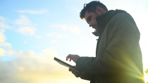 Outdoor, connection and man with a tablet, typing and lens flare with blue sky, network and website information. Person, environment and guy with technology, social media and digital app with nature. - Footage, Video