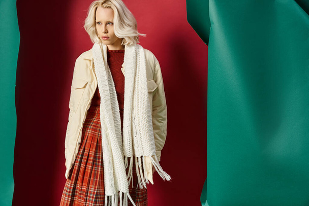 attractive blonde woman in winter outfit posing in white jacket on red with turquoise backdrop - Photo, Image