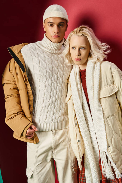 hombre y mujer de moda en ropa de abrigo de invierno posando juntos sobre fondo rojo y turquesa desgarrado - Foto, Imagen