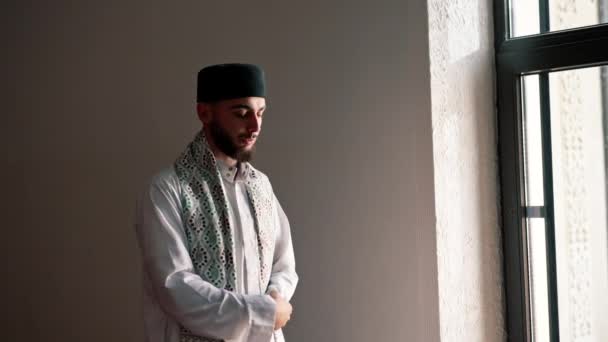 Silhouette d'un prêtre arabe qui se tient dans une mosquée en vêtements nationaux et prie Allah avec l'aide du Coran dans le Ramadan - Séquence, vidéo