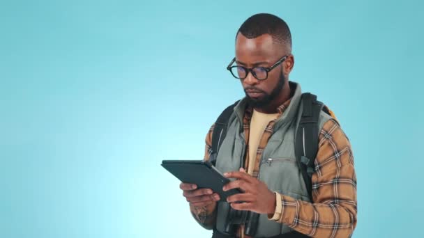 Πεζοπορία, tablet και μαύρο άνδρα σε μπλε φόντο για την επικοινωνία, το διαδίκτυο και την ιστοσελίδα. Ταξίδι, διακοπές και πρόσωπο στην ψηφιακή τεχνολογία για online τοποθεσία για περιπέτεια, διακοπές και πεζοπορία στο στούντιο. - Πλάνα, βίντεο