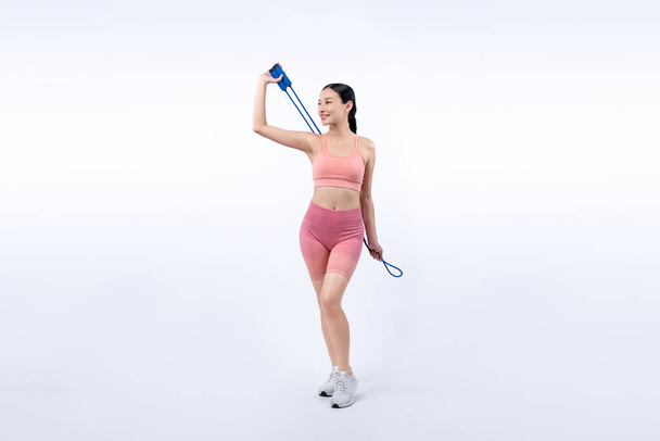 Jeune femme asiatique énergique en tenue de sport avec robe sautant ou sautant posant portrait en studio tourné sur fond isolé. Outil d'exercice cardio et mode de vie sain de soins du corps. Vigoureux - Photo, image