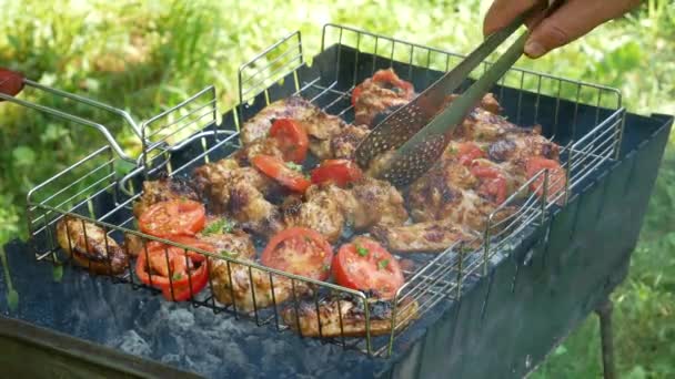 Fried chicken meats and tomatoes on the grill outdoors. B-B-Q. Fried food is fried and smoked on charcoal grills. It turns out a grill with delicious tasty chicken meats and vegetables. Slow motion. - Felvétel, videó