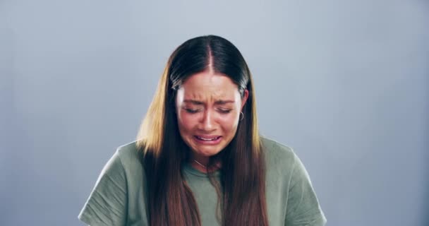 Smutna twarz i kobieta ze łzami w studio ze złamanym sercem po rozstaniu, rozwodzie lub złych wiadomościach. Emocje, zdenerwowanie i portret kobiety płaczącej z żalu, straty lub żałoby w szarym tle - Materiał filmowy, wideo