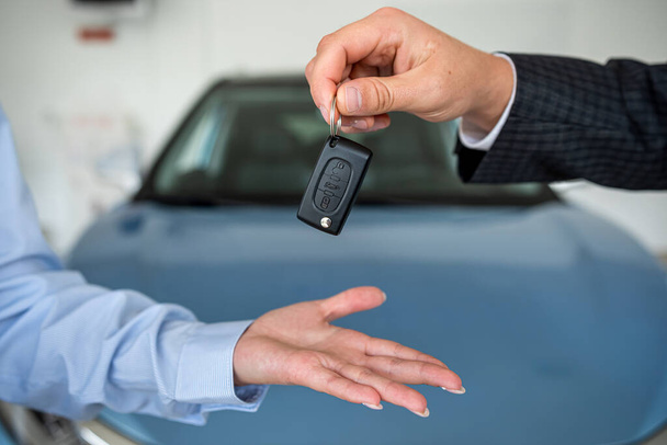 salesman give car key customer after success deal at modern showroom. close up. sale concept - Photo, Image