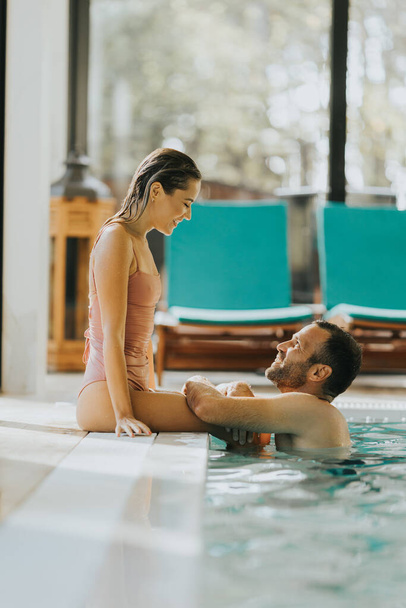 Hermosa pareja joven relajándose en la piscina cubierta - Foto, imagen