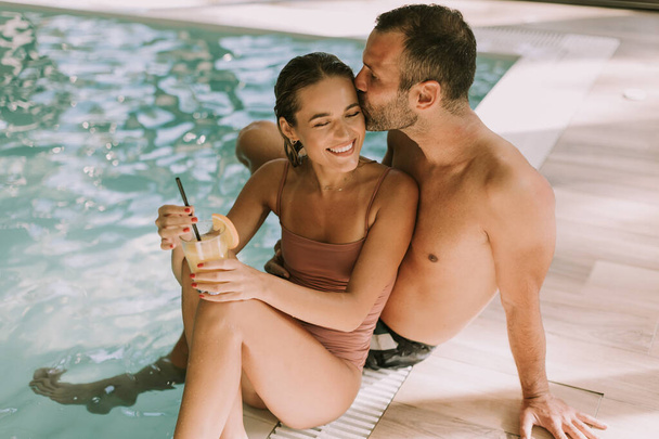 Bello giovane coppia rilassante presso la piscina coperta - Foto, immagini