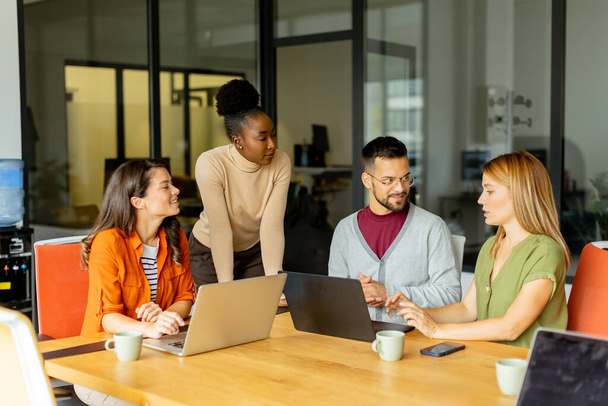 Молодая многонациональная команда стартапов работает в современном офисе - Фото, изображение