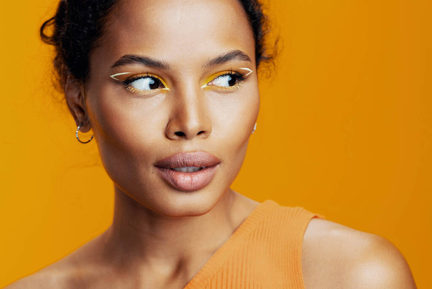 女性の美しい黄色いスペースモデル幸せなスタジオ美のファッションフェイス創造的な黒いスタイルのピンクのメイクアップの肌の化粧品コピーアフリカの民族的な化粧品の肖像画の笑顔 - 写真・画像