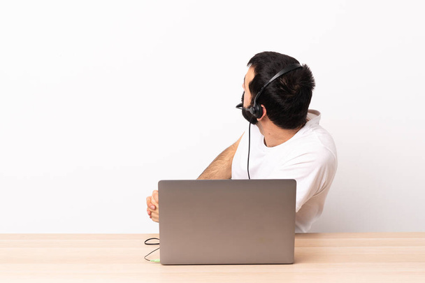 Telemarketer blanke man werken met een headset en met laptop in achterste positie. - Foto, afbeelding