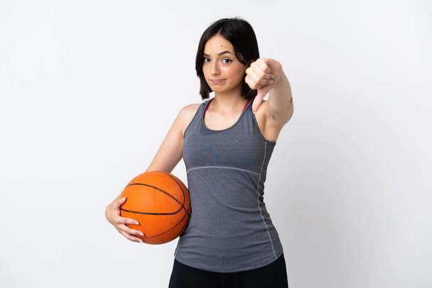 fiatal nő játszik kosárlabda elszigetelt fehér háttér mutatja hüvelykujj lefelé negatív kifejezés - Fotó, kép