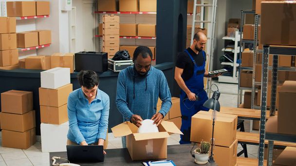 Employees putting products in boxes and dong highfive, celebrating stock shipment and delivery. Team of people working on retail development, shipping merchandise in packages. - Photo, Image