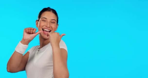 Woman, thumbs up and fitness studio with space, pointing and smile on face for promotion by blue background. Girl, sports and happy for health promo, exercise mockup and good review for feedback. - Footage, Video