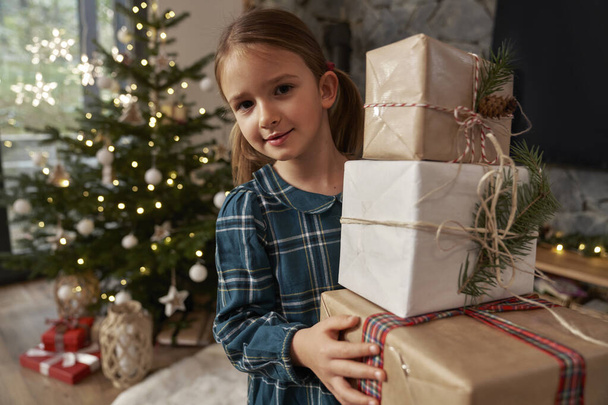 Elementary age girl carrying a pile of Christmas presents - Photo, Image