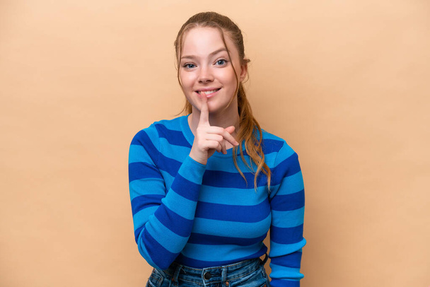 Young caucasian woman isolated on beige background showing a sign of silence gesture putting finger in mouth - Photo, Image