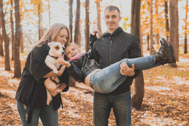 Familia pasar tiempo en el parque de otoño con un perro. Padre, madre e hija y Jack Russell terrier perro divertirse en otoño. - Foto, imagen