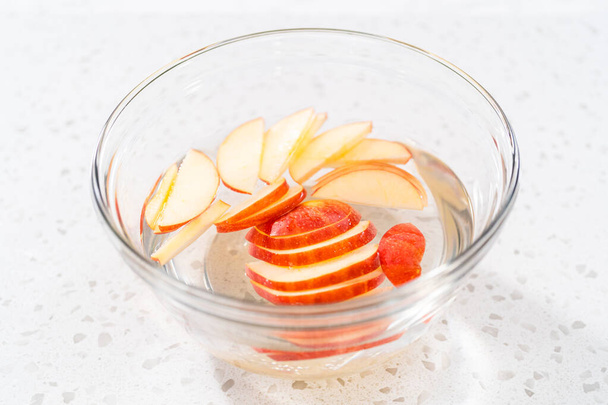Lavar las rodajas de manzana en la mezcla de agua para evitar que se doren. - Foto, Imagen