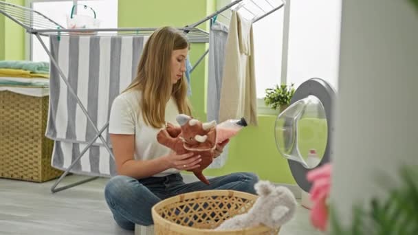 Herzerwärmende Szene, in der kaukasische Mutter und Tochter Hausarbeit teilen, Waschmittelflasche in der Hand halten, Spielzeug in der Waschküche zu Hause waschen - Filmmaterial, Video