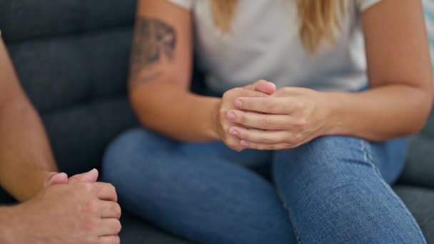 Man and woman couple sitting on sofa with hands together at home - Materiał filmowy, wideo