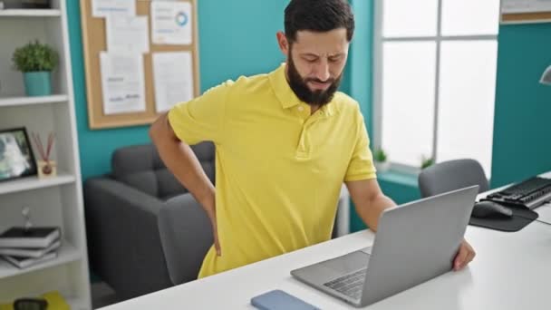 Νέος ισπανόφωνος επιχειρηματίας που χρησιμοποιεί φορητό υπολογιστή που υποφέρει για οσφυαλγία στο γραφείο - Πλάνα, βίντεο