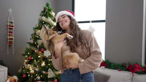 Young hispanic woman with dog celebrating christmas dancing at home - Footage, Video