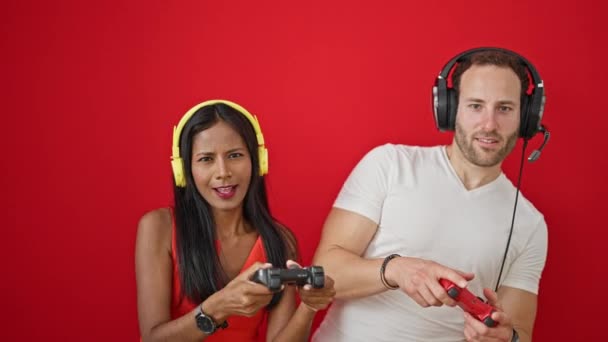 Gyönyörű pár mosolygós magabiztos videojáték elszigetelt piros háttér - Felvétel, videó