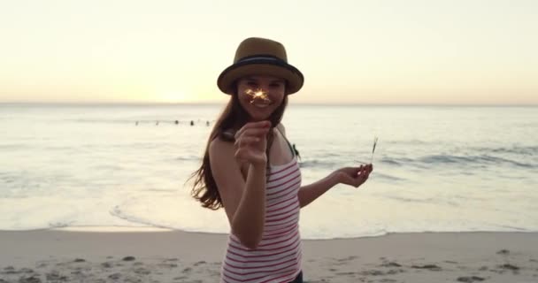 Woman, cheerful and ocean with fireworks, dance and enjoy the beach, nature and seaside. Travel, holiday and smile for vacation, calm and peace with freedom, trip and outdoor to relax, hat and play. - Footage, Video