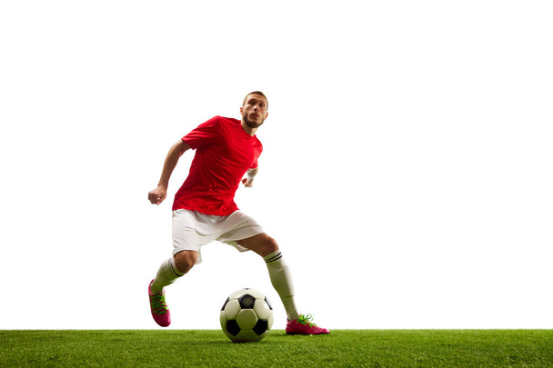 Professional soccer player looks confident in sportwear and boots training, playing, kicking ball isolated over white studio background. Concept of game, sport, recreation, active lifestyle. - Photo, Image