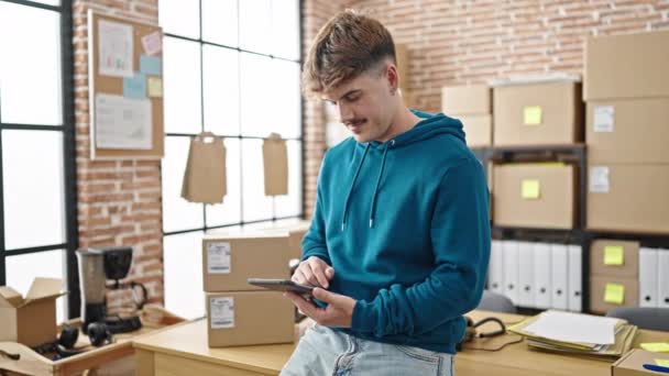Młody latynoski człowiek e-commerce pracownik za pomocą touchpad uśmiechnięty w biurze - Materiał filmowy, wideo